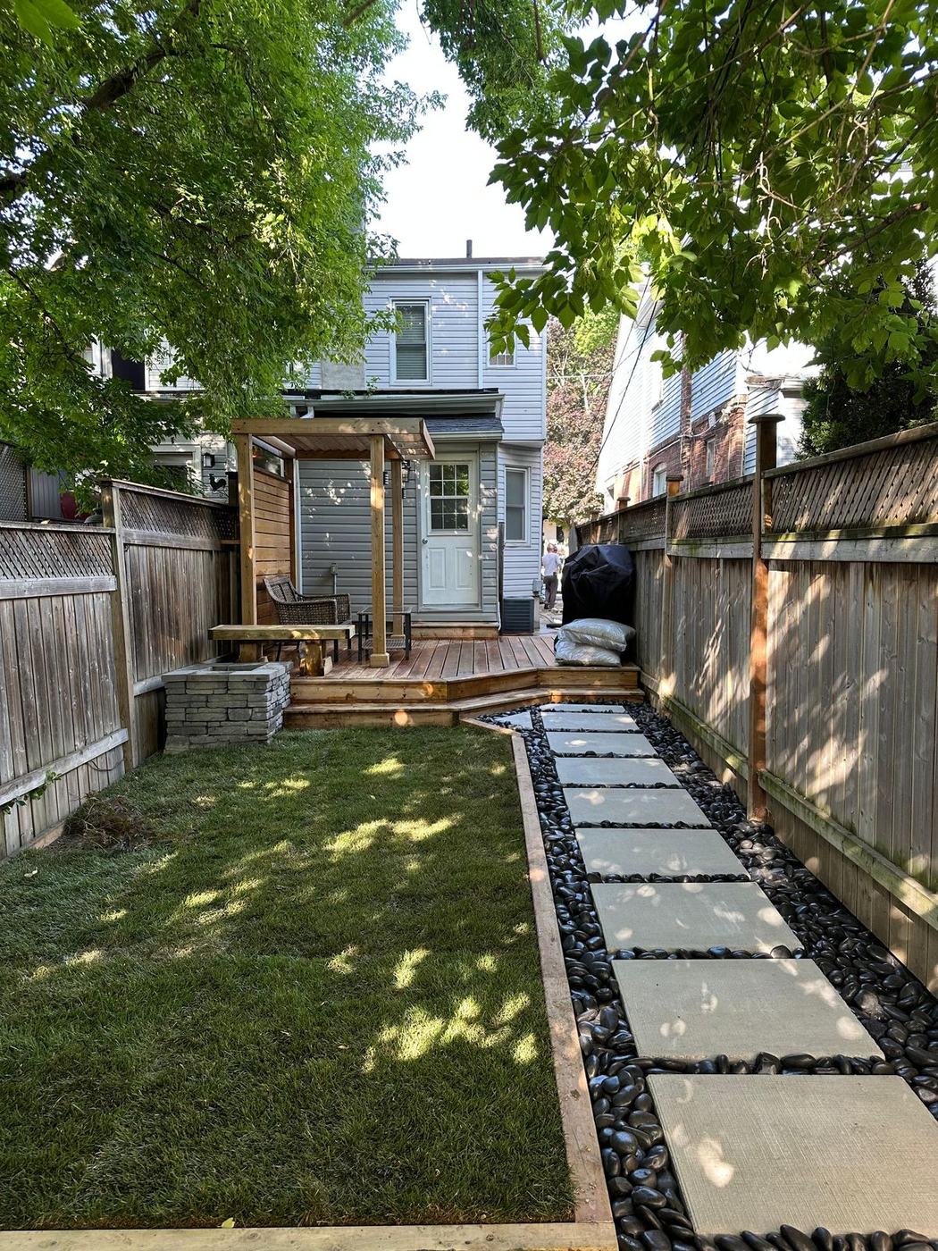 Narrow city backyard with new sod, stepping stones and river rock