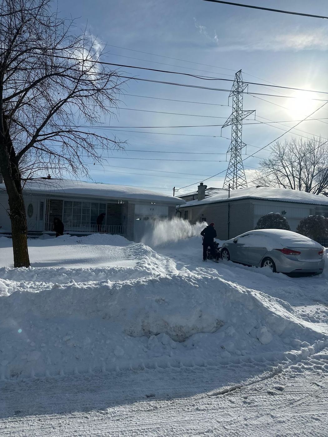 Crew member clearing a residential driveway with a snow blower