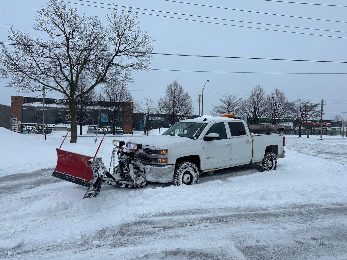 Ramada plow truck with a salt spreader clearing a commercial lot